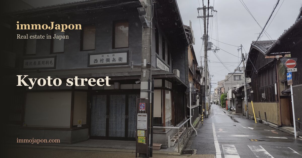 Teramachi street in the Shimogyo ward of Kyoto: two-storey dark timber townhouses lined along a narrow rain-soaked street, utility poles and small shop signs, the typical urban fabric of central Kyoto