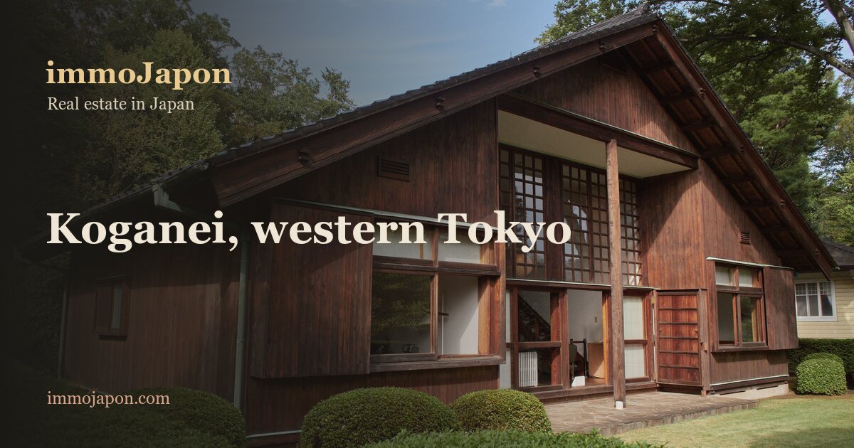 An old timber house with dark wooden walls, a tall gabled roof and lattice windows, set among trees and clipped hedges in Koganei, in the Tama area of western Tokyo
