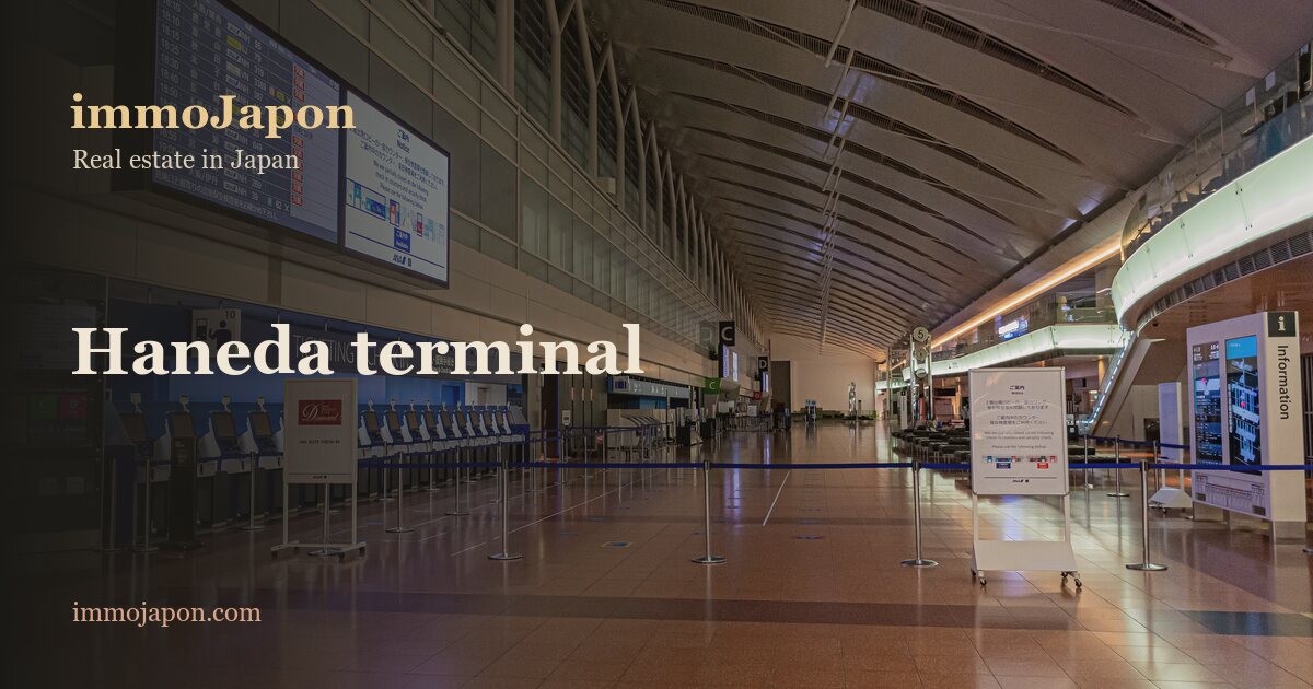 The empty departure hall of Terminal 2 at Tokyo Haneda Airport: a long curved glass roof braced by steel arches lights a row of closed blue check-in counters, a polished stone floor reflecting the suspended information screens, and a few signage boards in the foreground